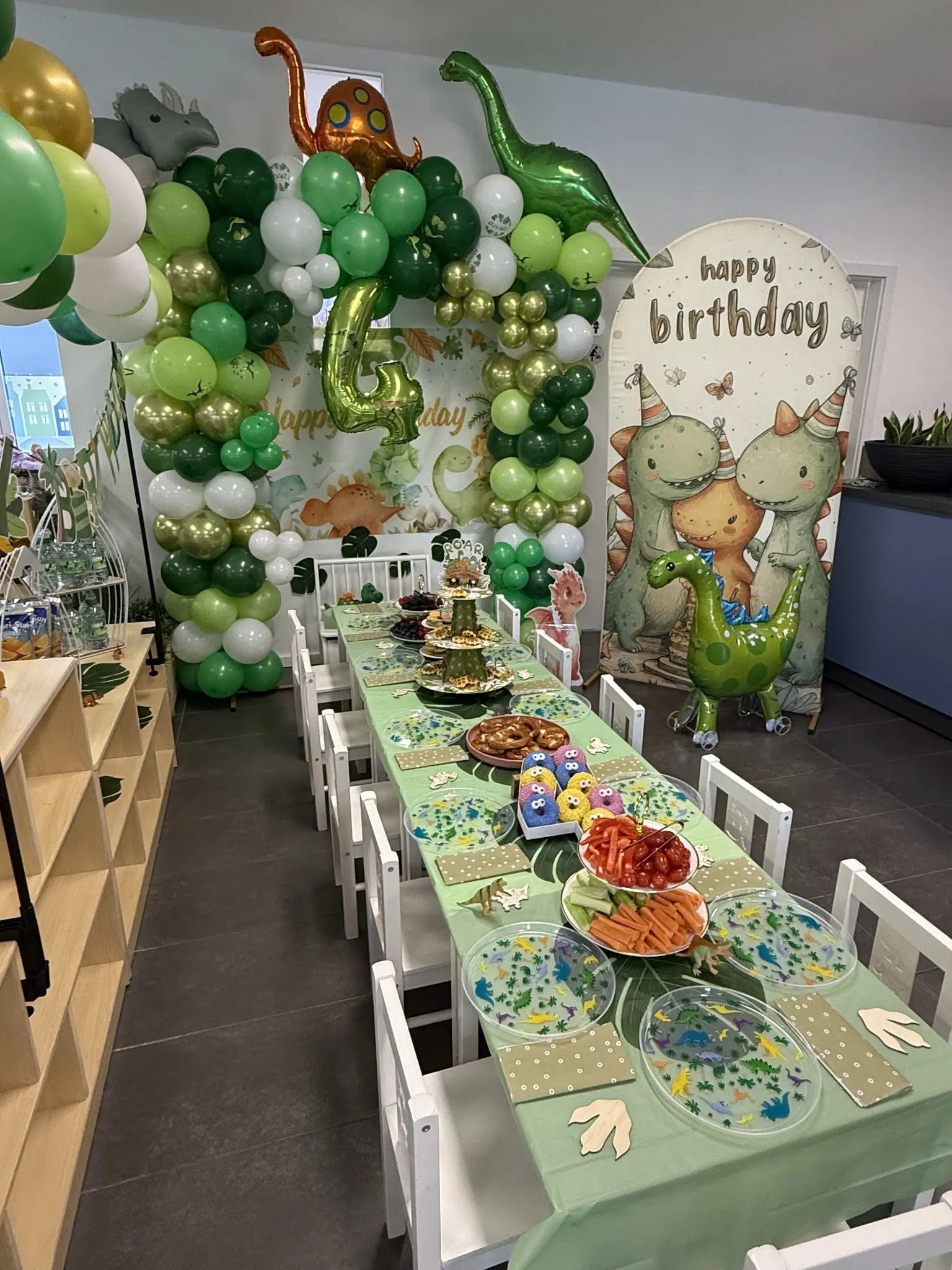 Dinosaurier-Geburtstag mit grüner Ballondekoration und gedecktem Kindertisch