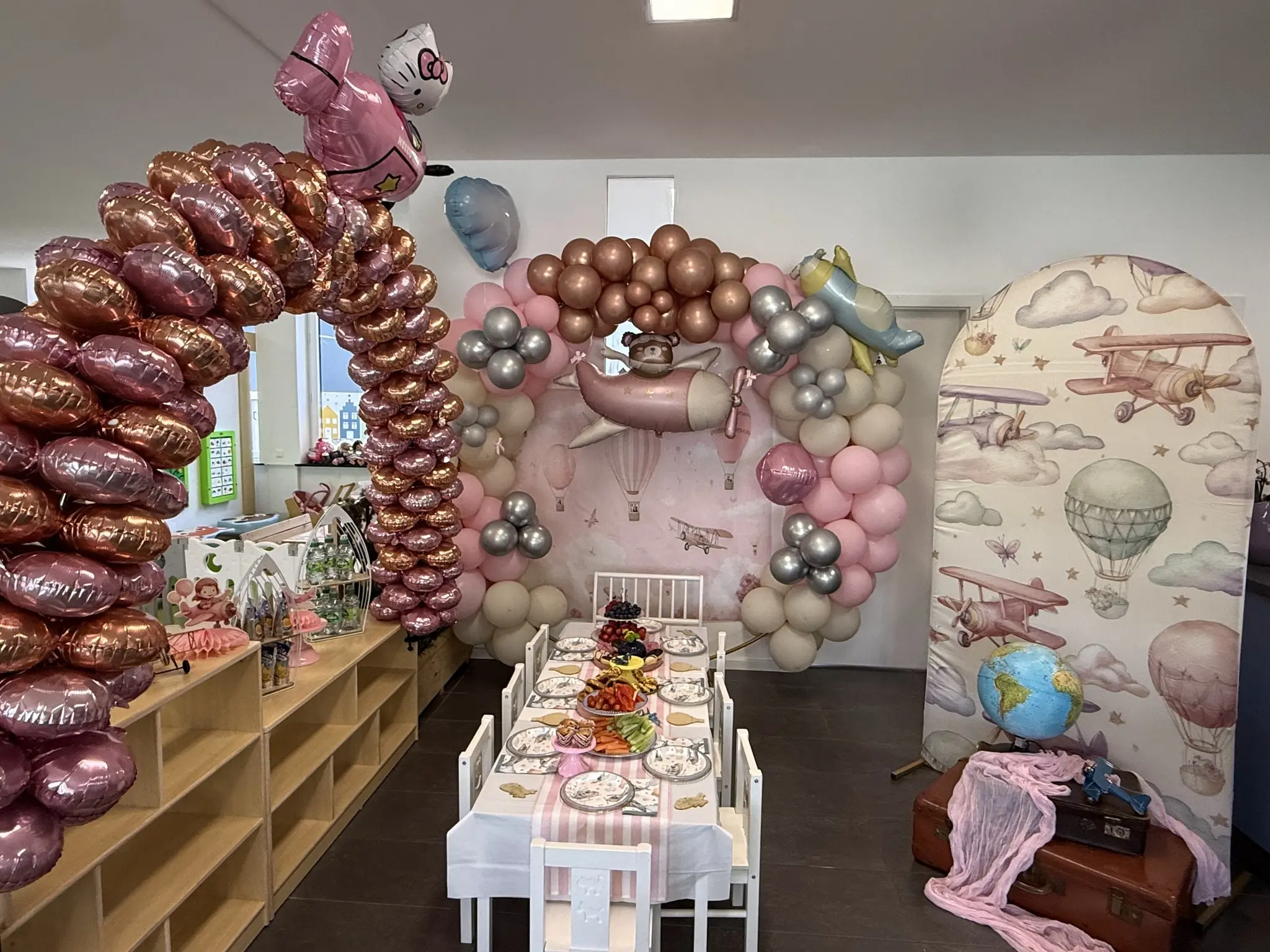 Flugzeug-Geburtstagsdekoration mit rosa Ballons und festlicher Tafel