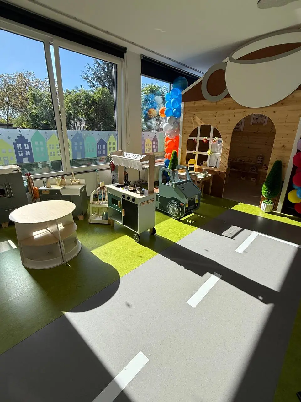 Sonniger Rollenspielbereich mit Kinderküche, Spielstraße und Caféhaus